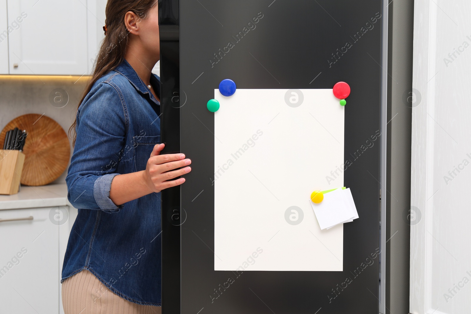 Photo of Woman opening refrigerator with blank magnetic board and note in kitchen, closeup