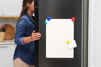 Woman opening refrigerator with blank magnetic board and note in kitchen, closeup