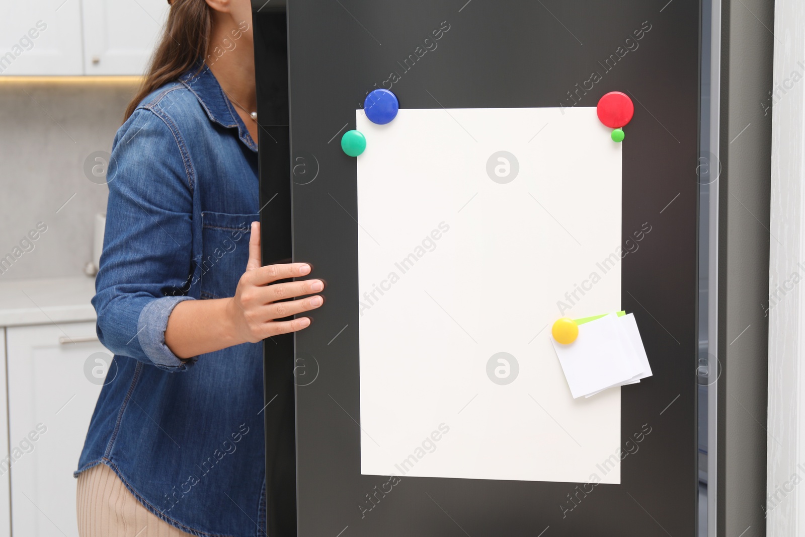 Photo of Woman opening refrigerator with blank magnetic board and note in kitchen, closeup