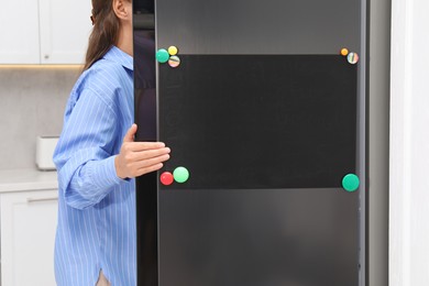 Photo of Woman opening refrigerator with blank magnetic board in kitchen, closeup