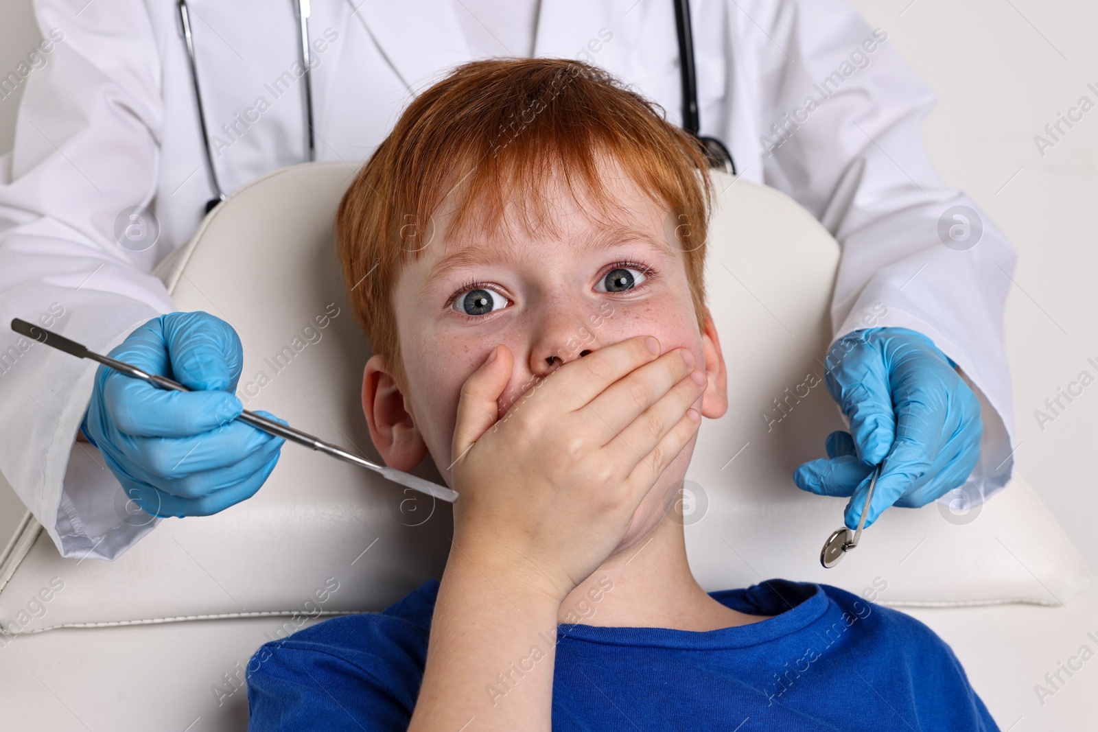 Photo of Dental phobia. Dentist working with scared little boy