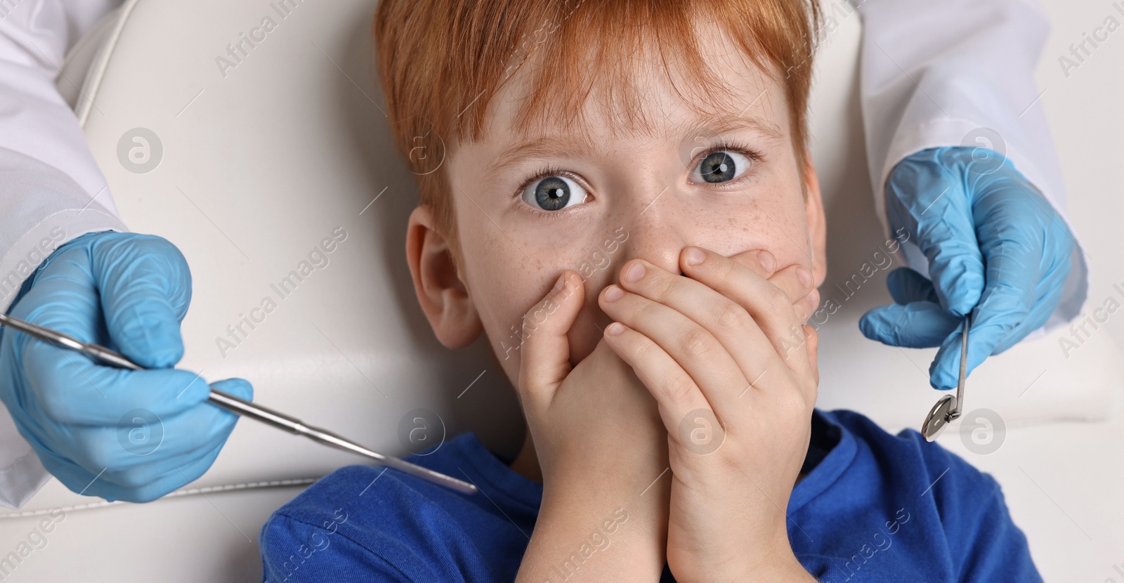 Photo of Dental phobia. Dentist working with scared little boy