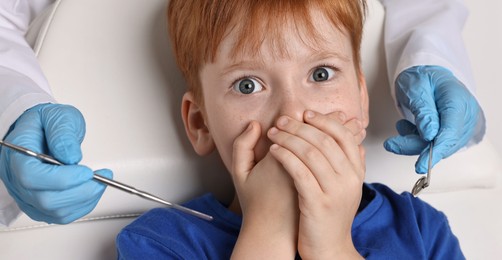 Photo of Dental phobia. Dentist working with scared little boy