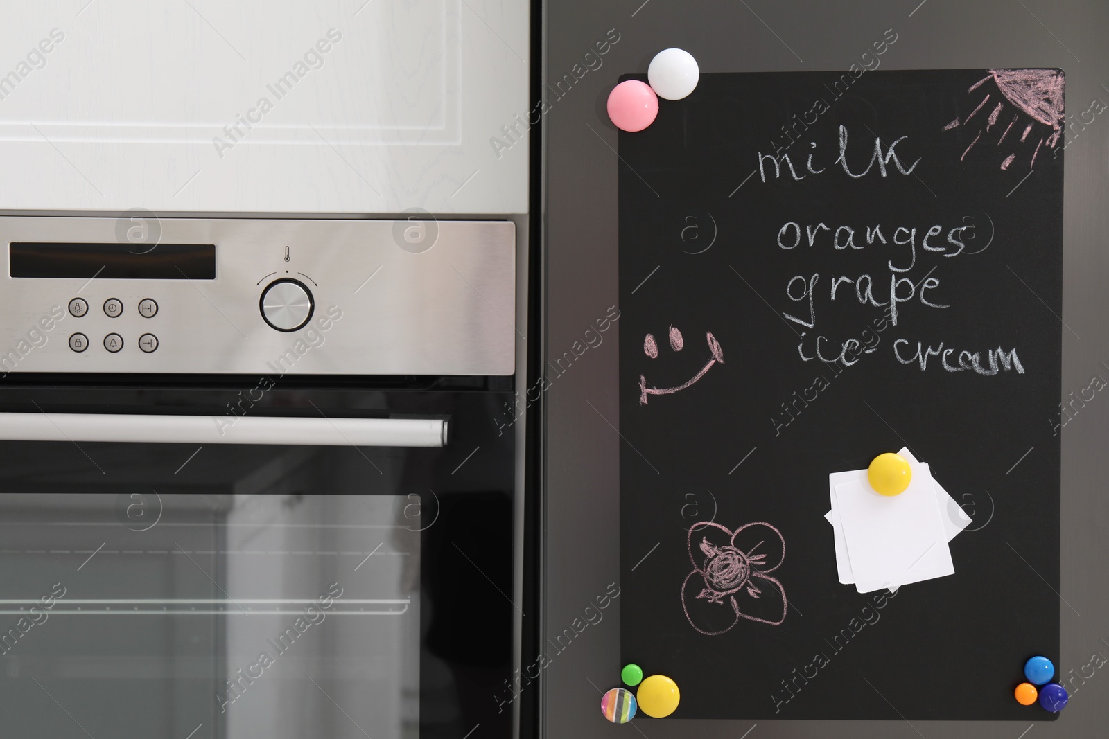 Photo of Magnetic board with shopping list and notes on refrigerator in kitchen