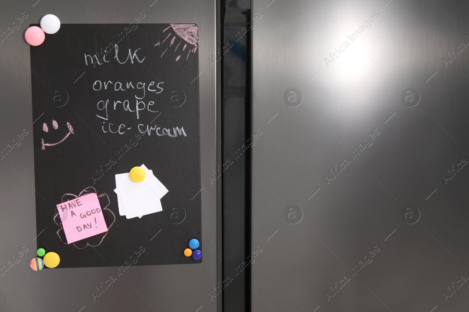 Photo of Magnetic board with shopping list and notes on refrigerator in kitchen