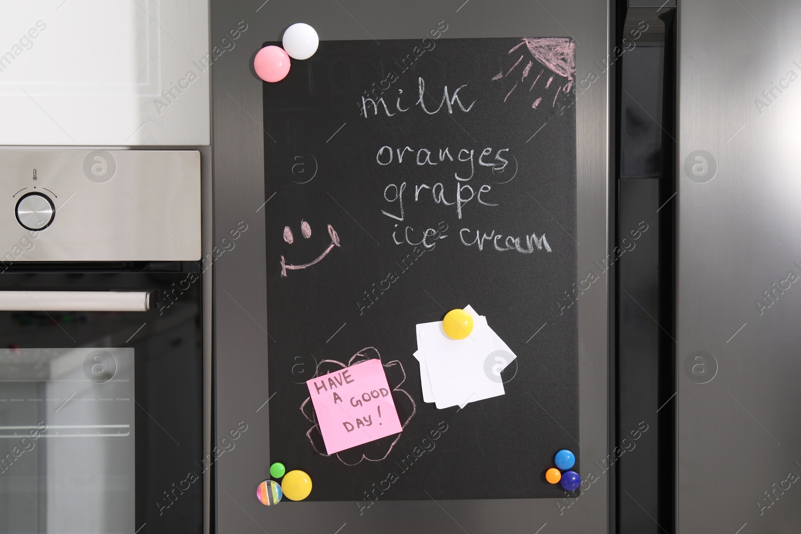 Photo of Magnetic board with shopping list and notes on refrigerator in kitchen