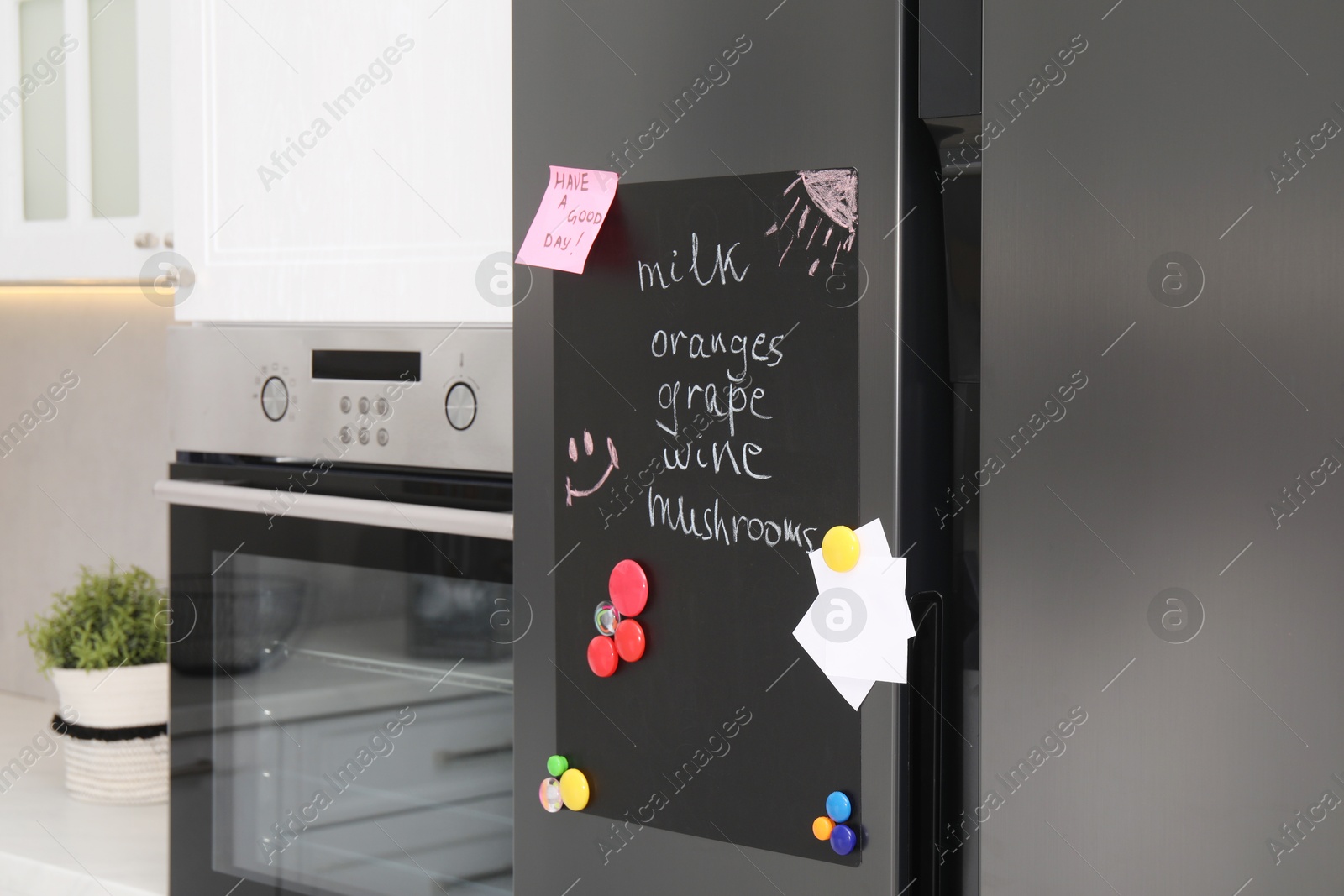 Photo of Magnetic board with shopping list and notes on refrigerator in kitchen