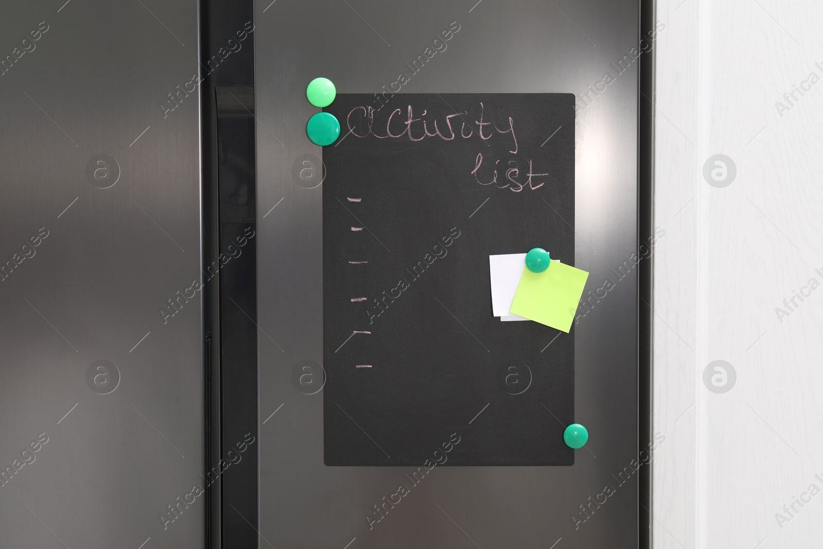 Photo of Magnetic board with activity list and notes on refrigerator in kitchen