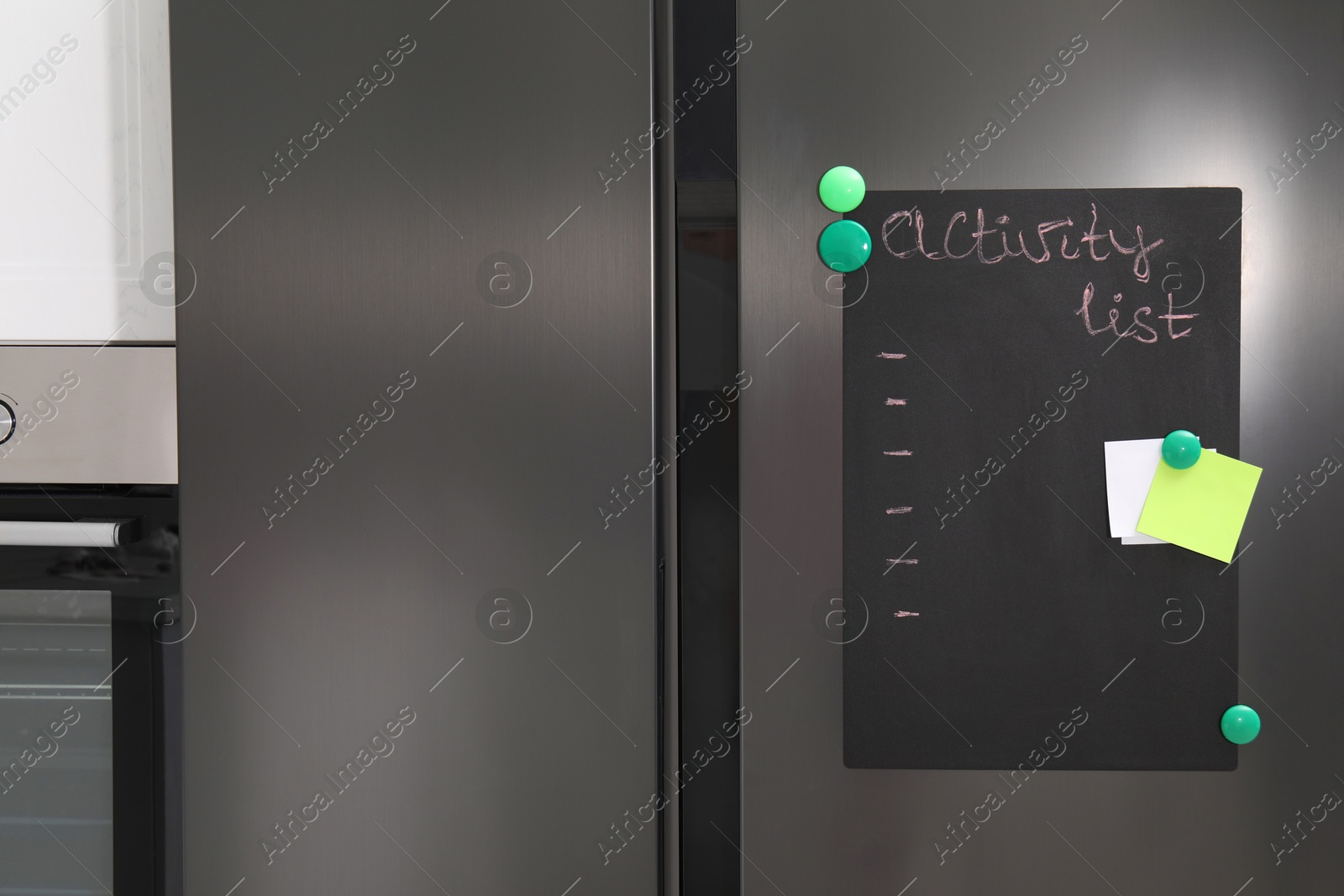 Photo of Magnetic board with activity list and notes on refrigerator in kitchen