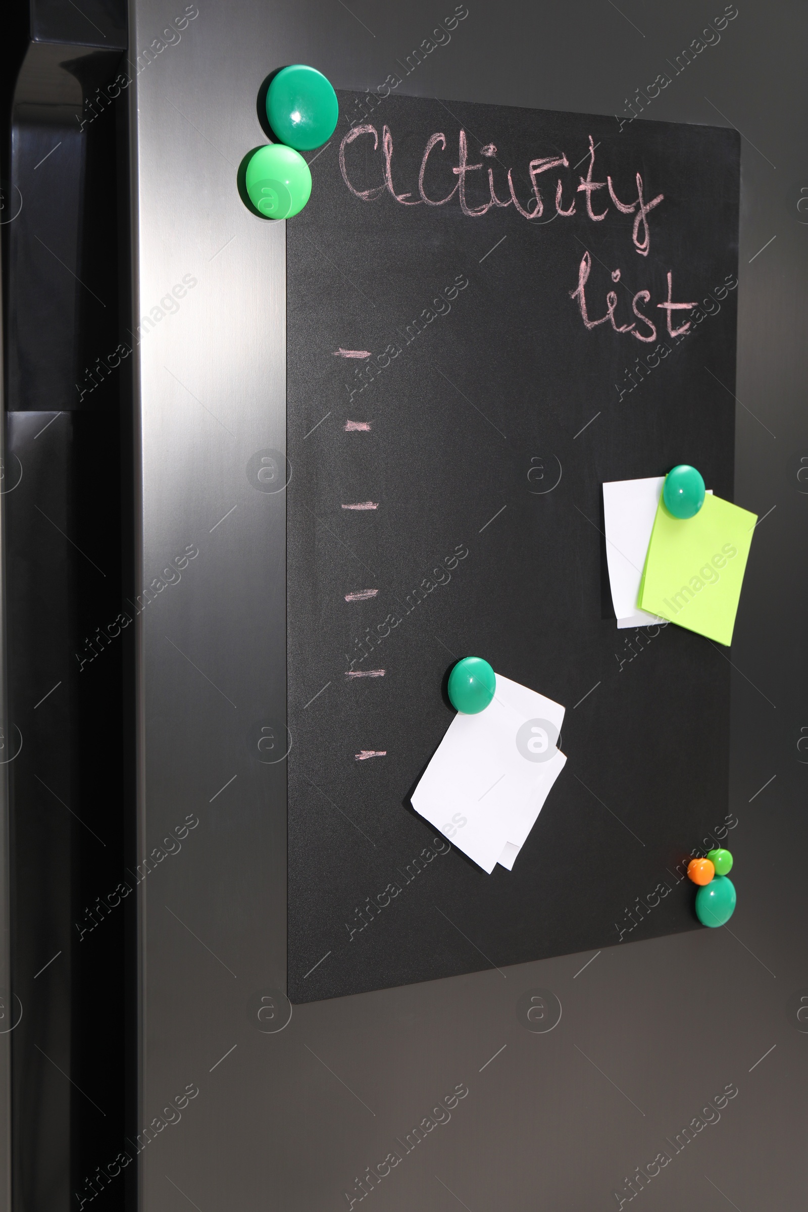 Photo of Magnetic board with activity list and notes on refrigerator in kitchen