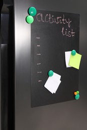 Magnetic board with activity list and notes on refrigerator in kitchen