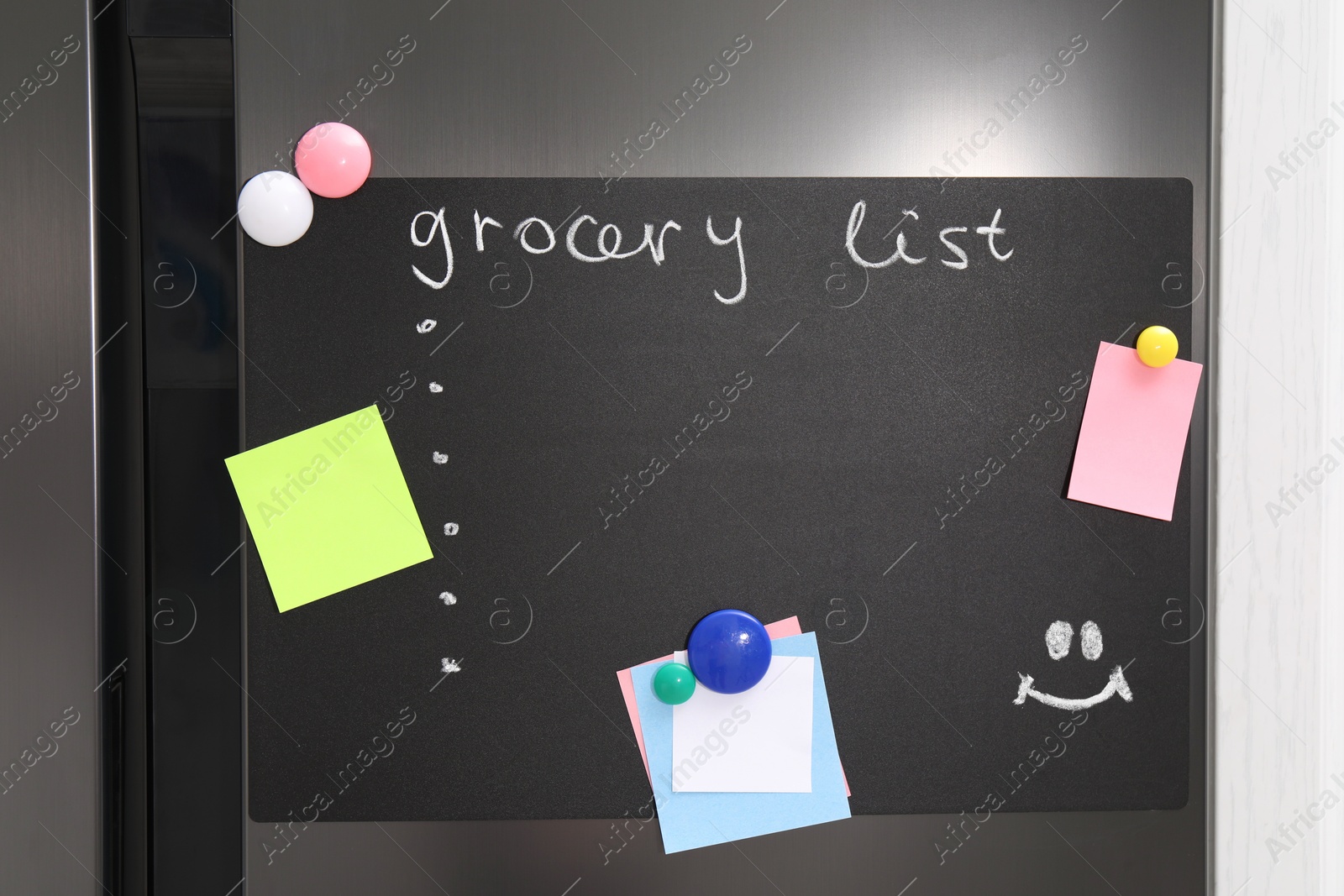 Photo of Magnetic board with grocery list and notes on refrigerator in kitchen