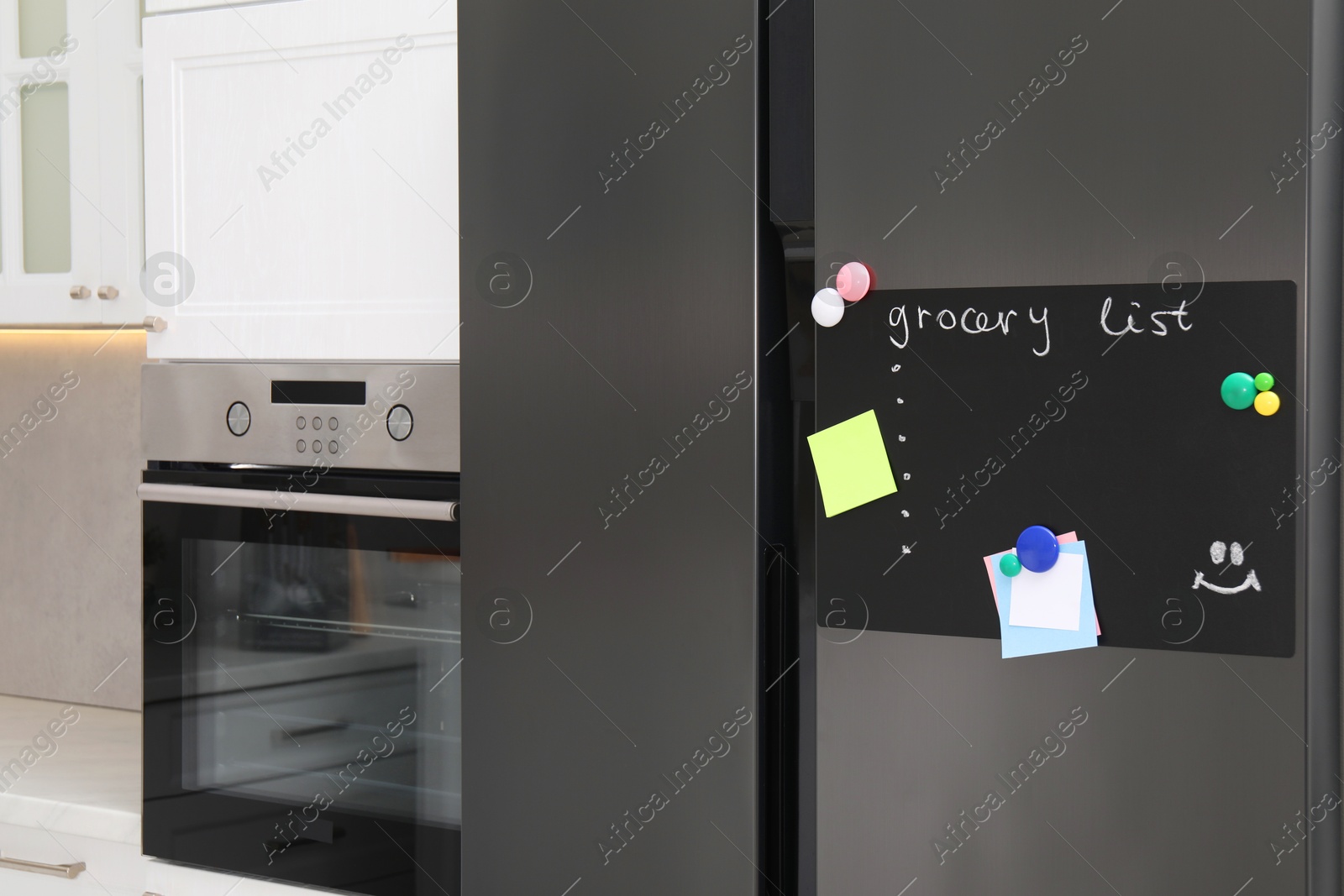 Photo of Magnetic board with grocery list and notes on refrigerator in kitchen