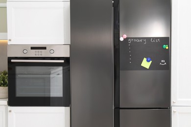 Magnetic board with grocery list and note on refrigerator in kitchen