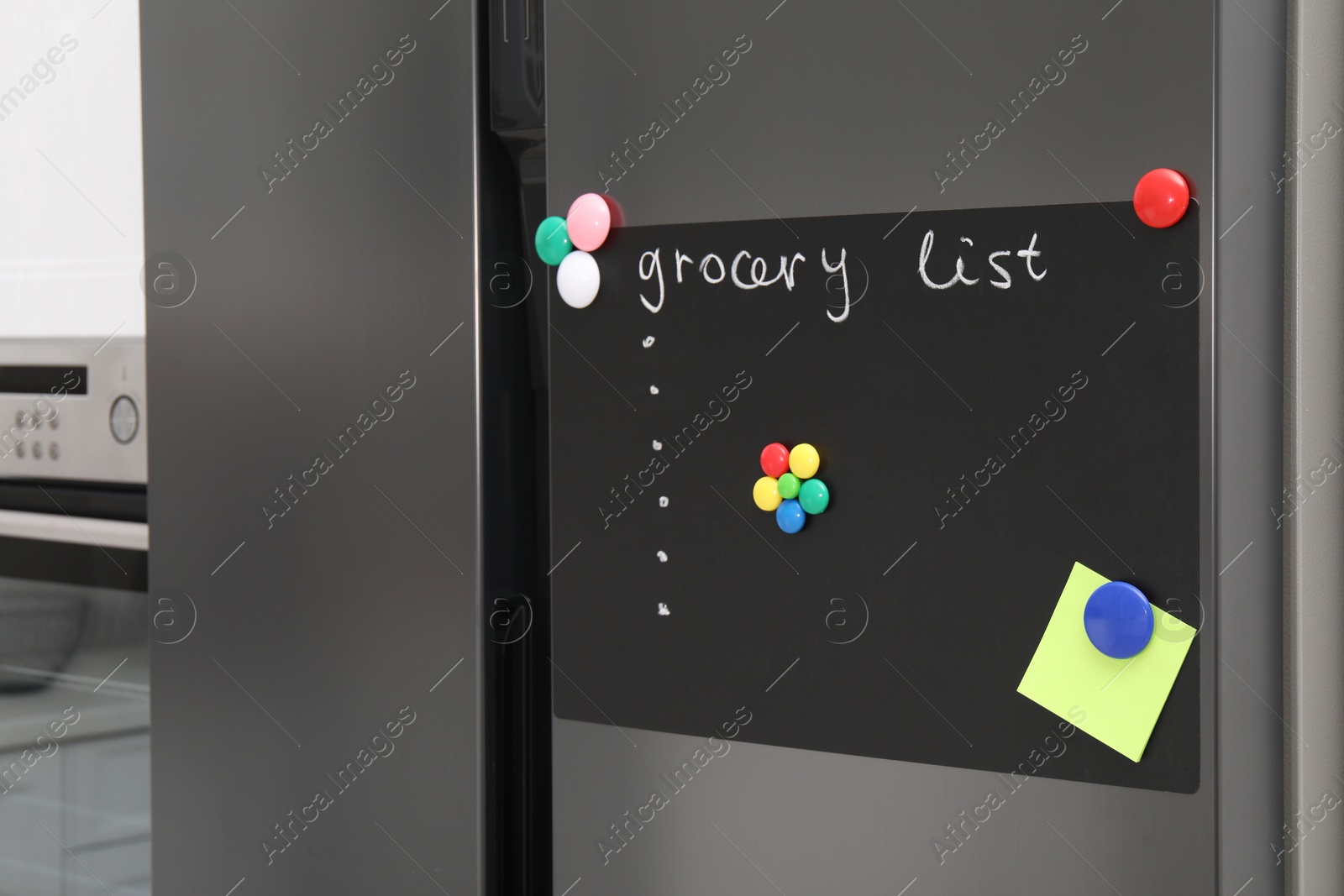 Photo of Magnetic board with grocery list and note on refrigerator in kitchen