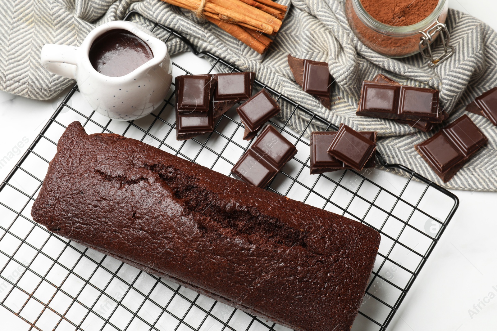 Photo of Tasty chocolate sponge cake and ingredients on white marble table, flat lay