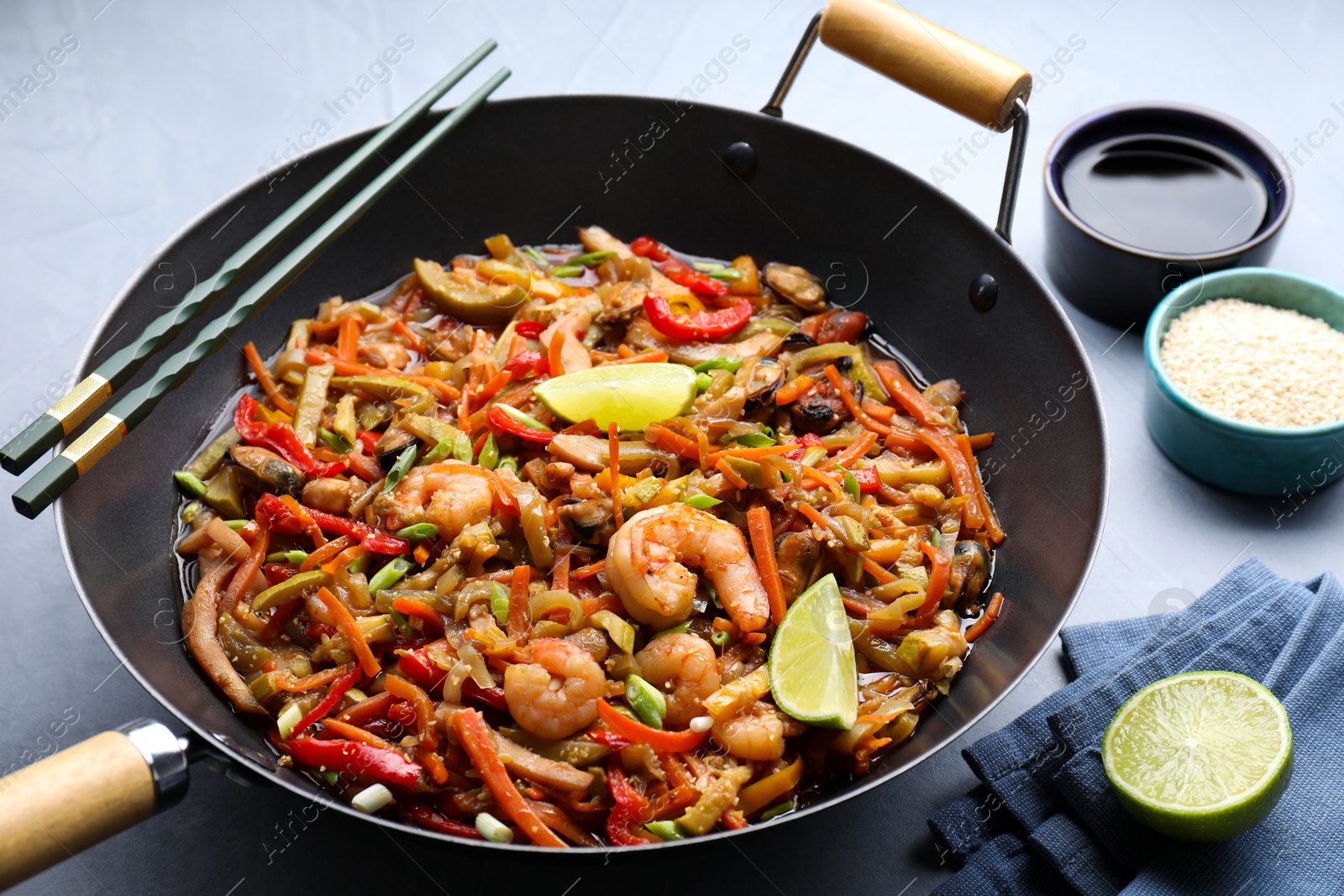 Photo of Stir-fry sea food in wok served on grey table