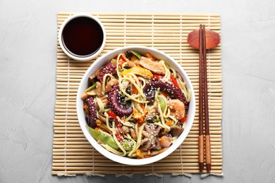 Stir-fry noodles with sea food served on light grey table, flat lay