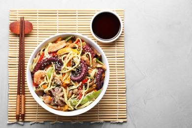 Stir-fry noodles with sea food served on light grey table, flat lay. Space for text