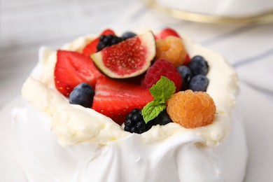 Photo of Pavlova cake (meringue dessert) with whipped cream, fresh berries, fig and mint on table, closeup