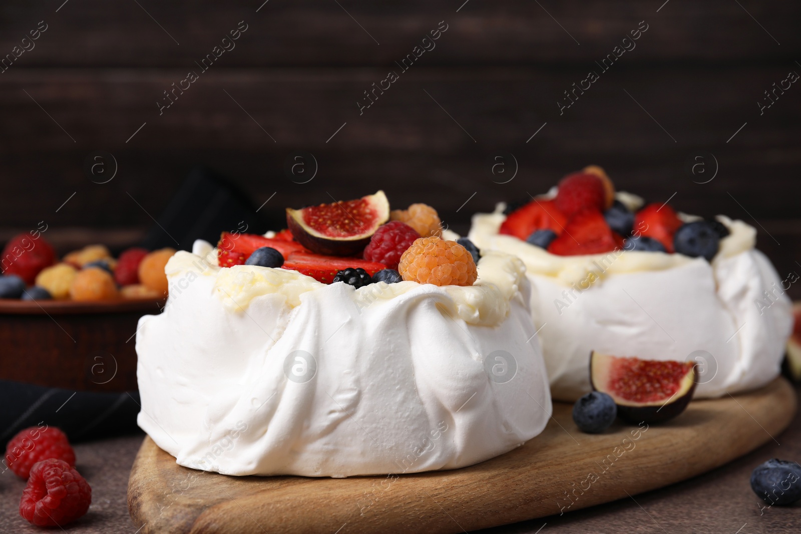 Photo of Pavlova cake (meringue dessert) with whipped cream, fresh berries and fig on brown table, closeup