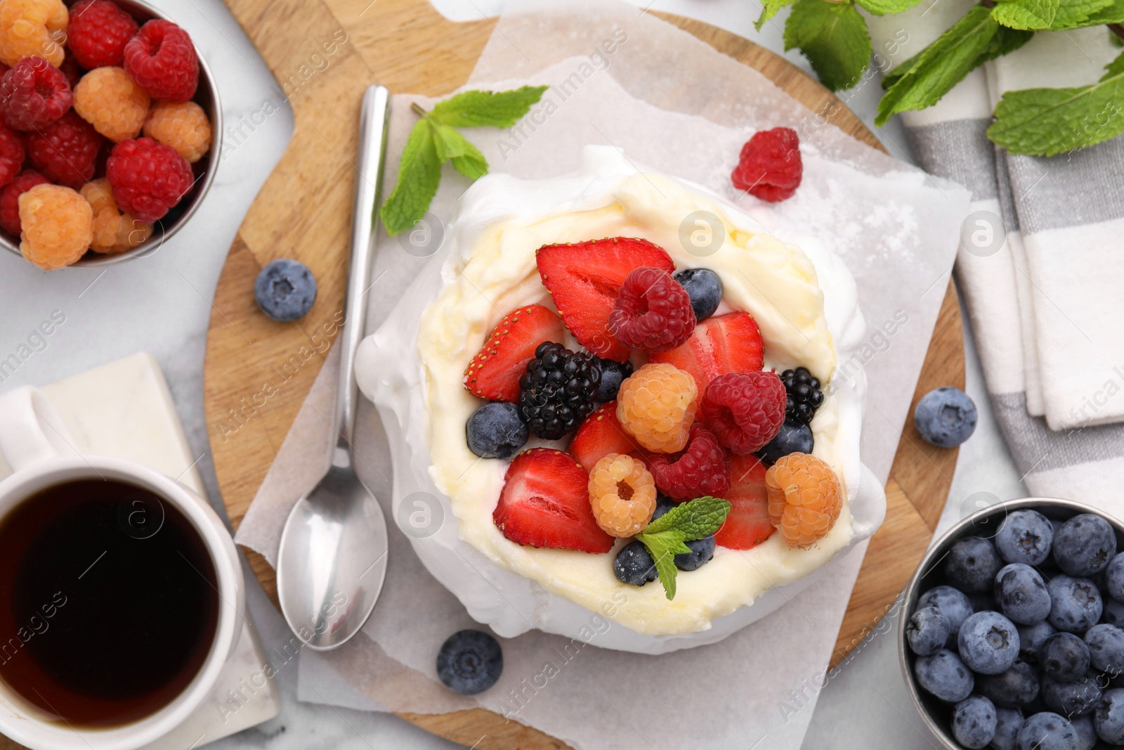 Photo of Pavlova cake (meringue dessert) with whipped cream, fresh berries and mint on table, flat lay