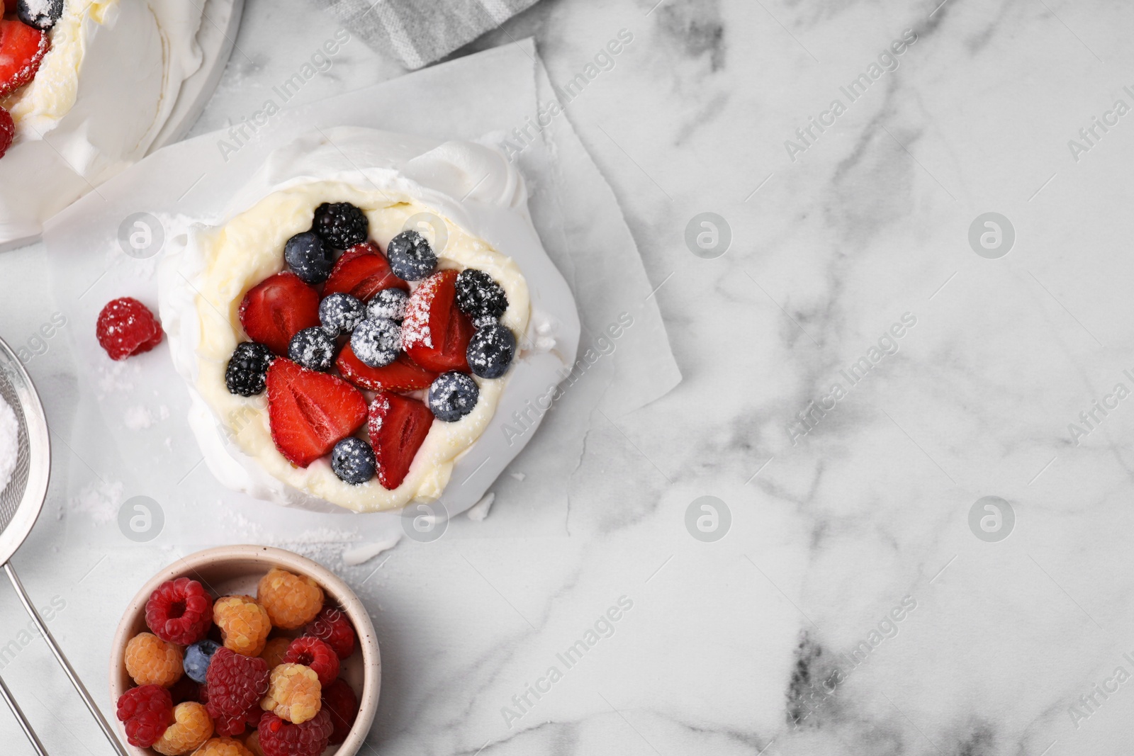 Photo of Pavlova cake (meringue dessert) with whipped cream, fresh berries and powdered sugar on white marble table, flat lay. Space for text