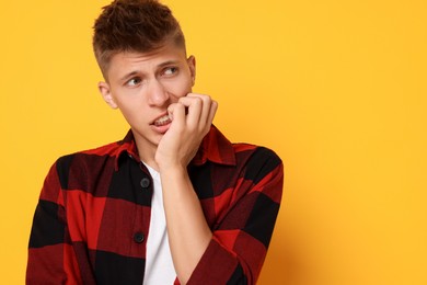 Portrait of scared young man on orange background, space for text