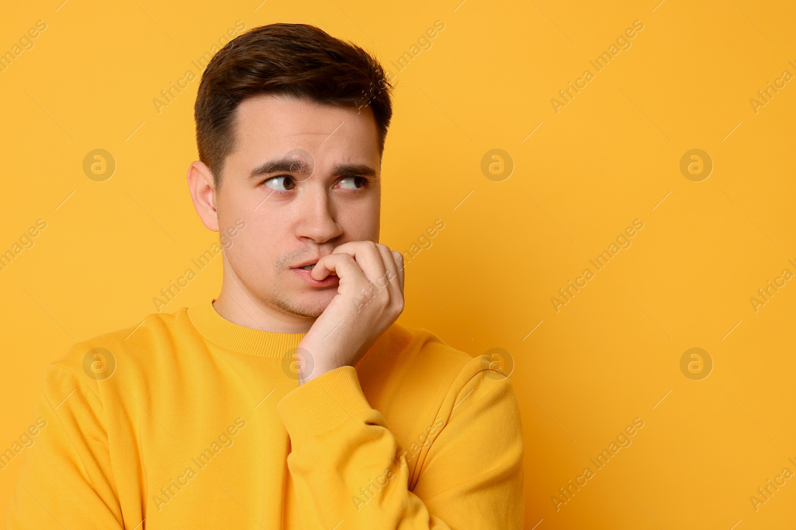 Photo of Portrait of scared young man on orange background, space for text