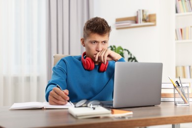 Student with headphones studying at table indoors