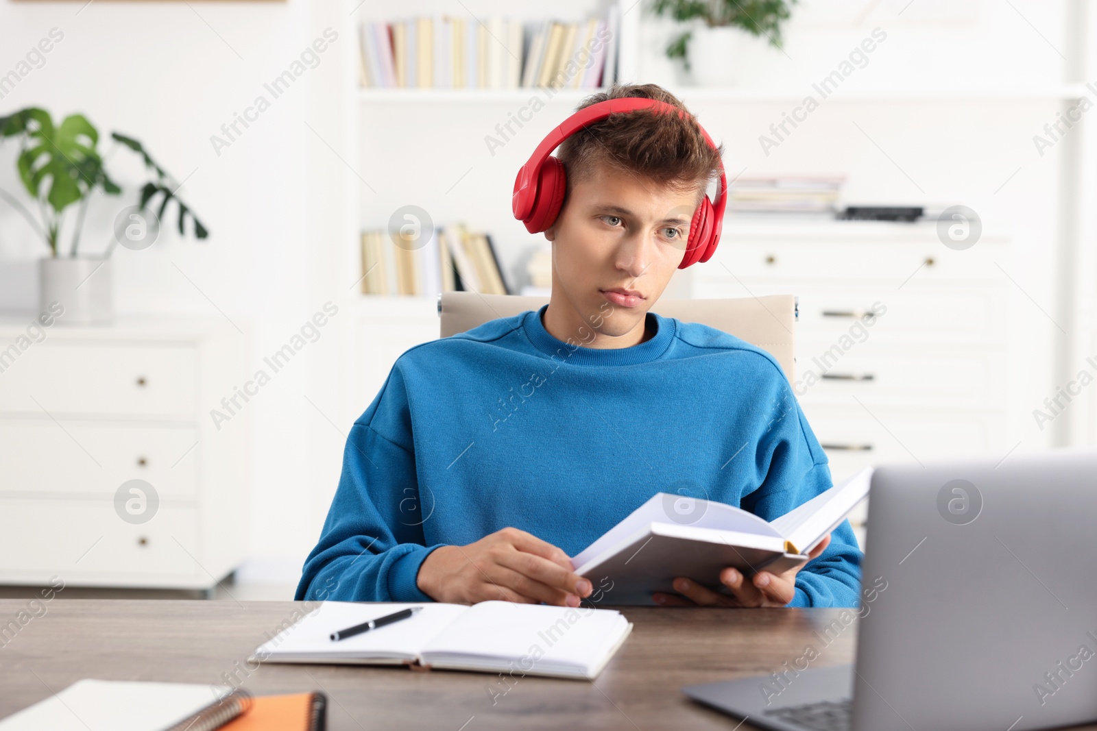 Photo of Student in headphones studying at table indoors