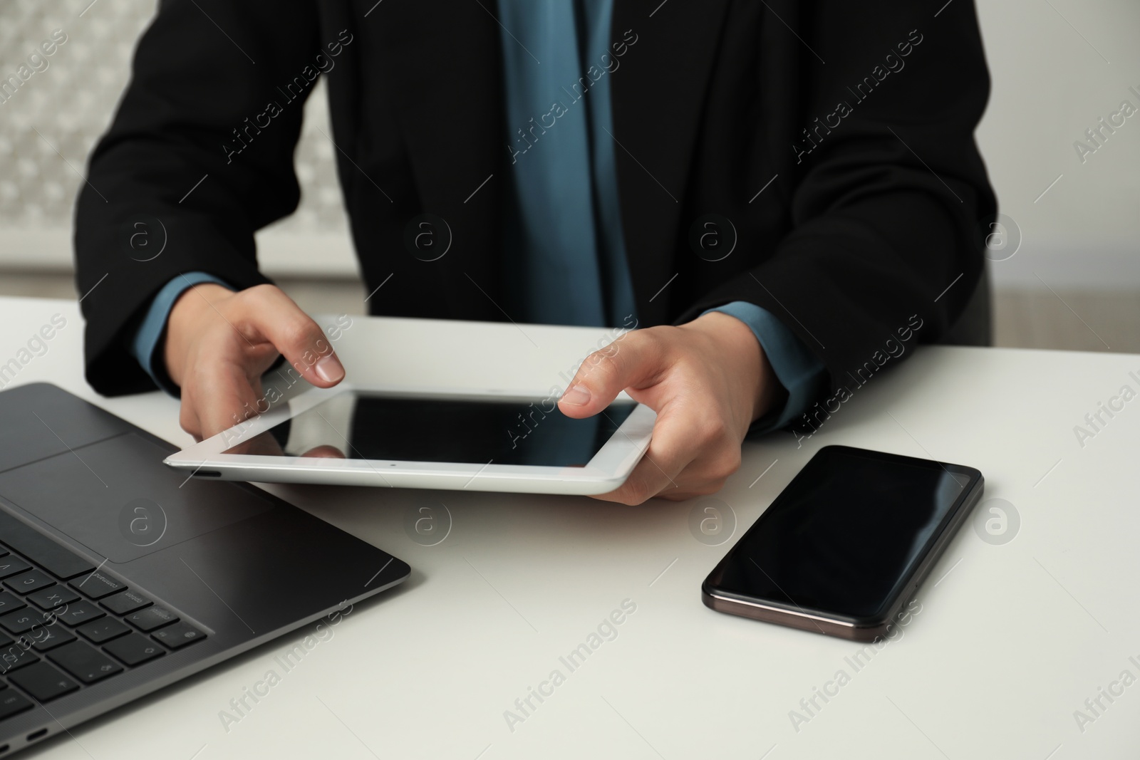 Photo of Businesswoman using tablet at white table indoors, closeup. Modern technology