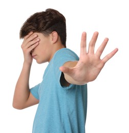 Scared teenage boy covering face with hand on white background