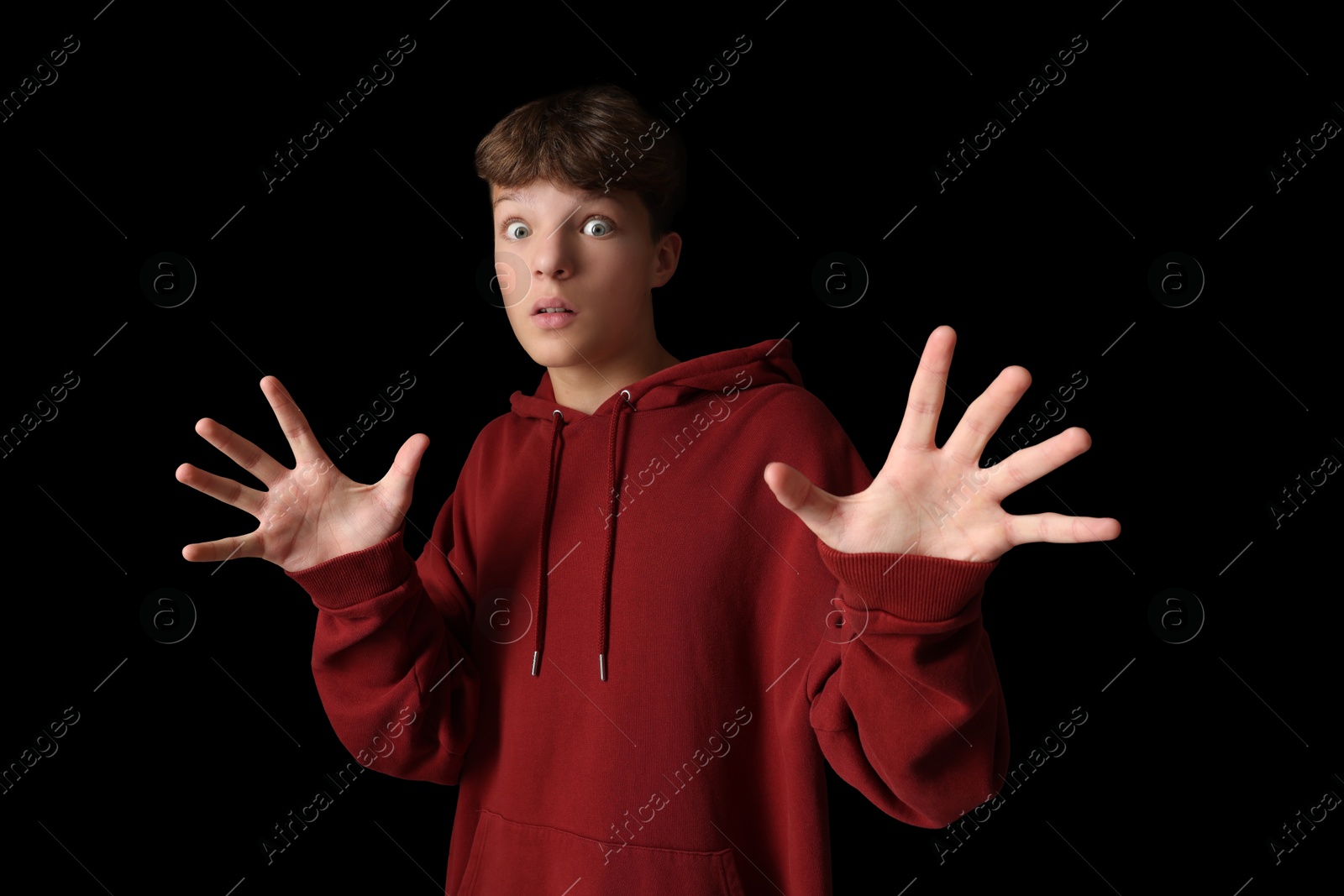 Photo of Portrait of scared teenage boy on black background