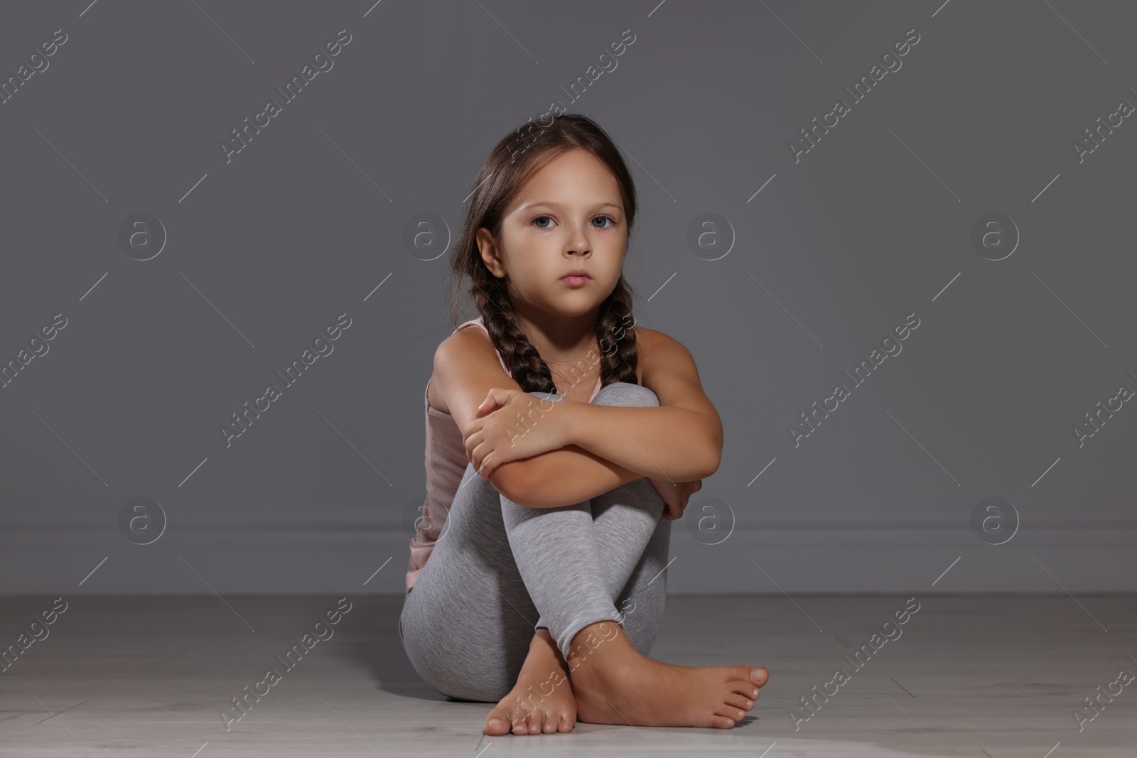 Photo of Orphanage concept. Sad girl sitting on floor indoors