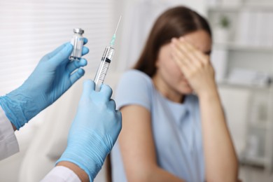 Dental phobia. Dentist with syringe near scared woman in clinic, selective focus