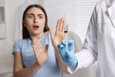 Dental phobia. Dentist with syringe near scared woman in clinic, selective focus