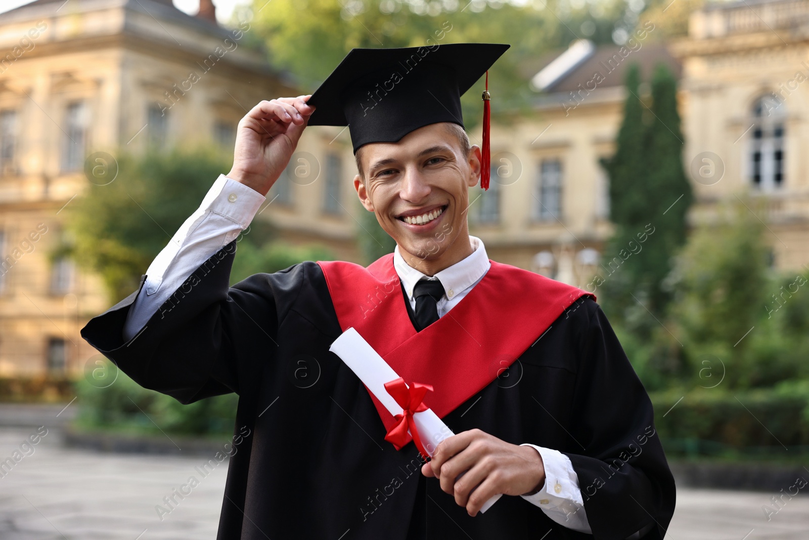 Photo of Happy student with diploma after graduation ceremony outdoors