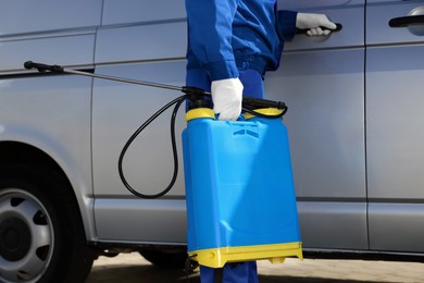 Pest control worker with spray tank near gray minibus outdoors, closeup