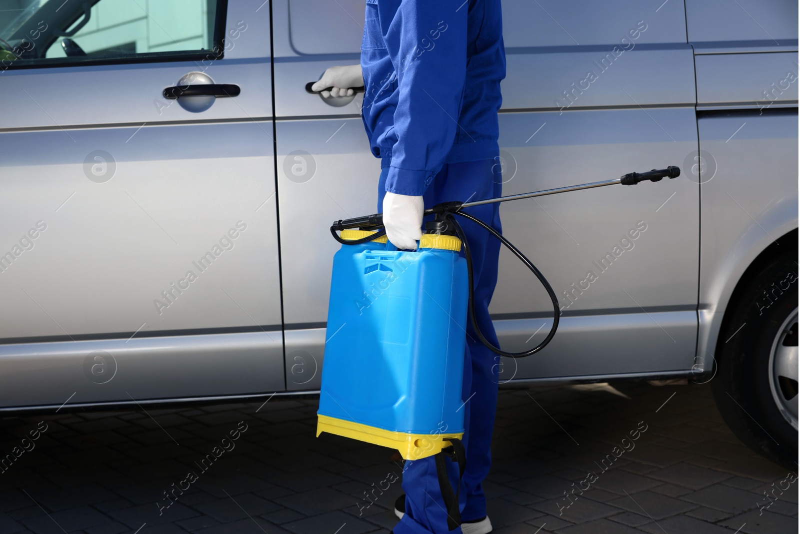 Photo of Pest control worker with spray tank near gray minibus outdoors, closeup