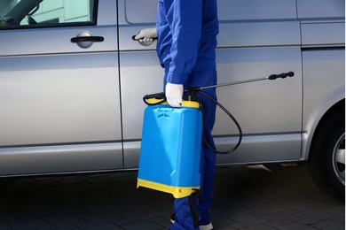 Pest control worker with spray tank near gray minibus outdoors, closeup