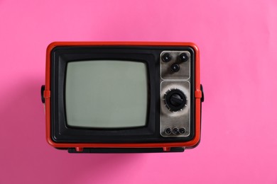 Photo of Retro tv set on pink background, top view