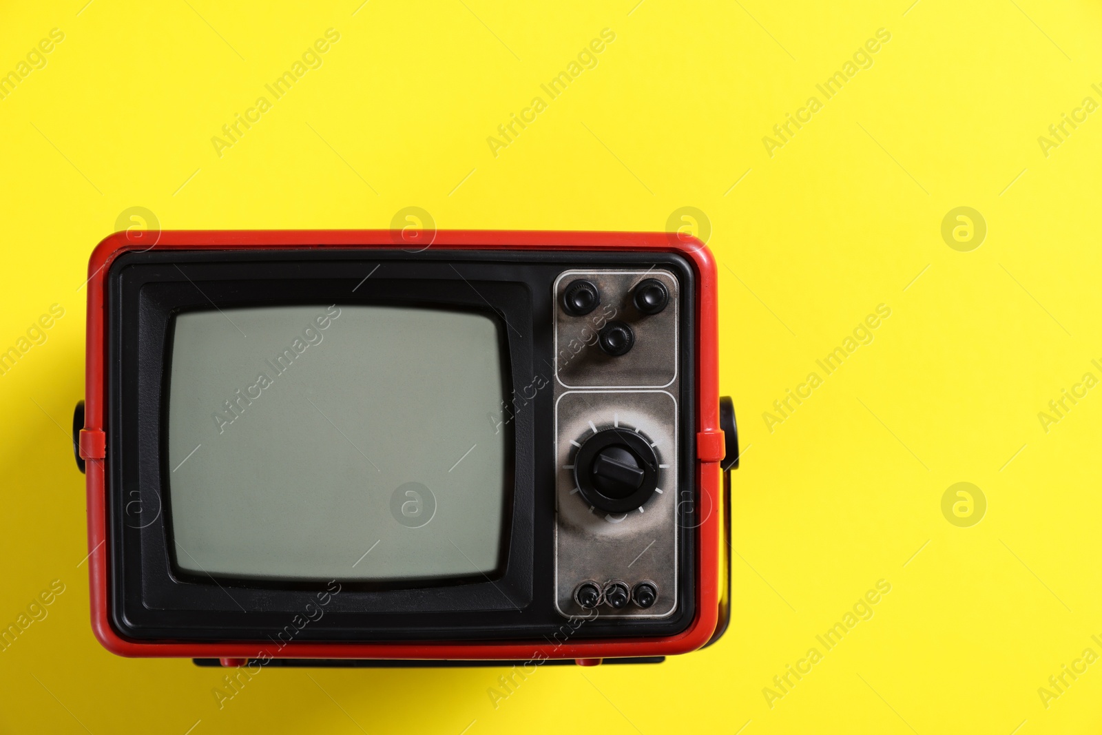 Photo of Retro tv set on yellow background, top view. Space for text