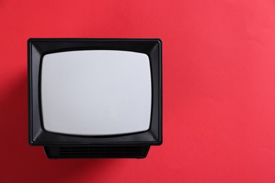 Photo of Retro tv set on red background, top view. Space for text