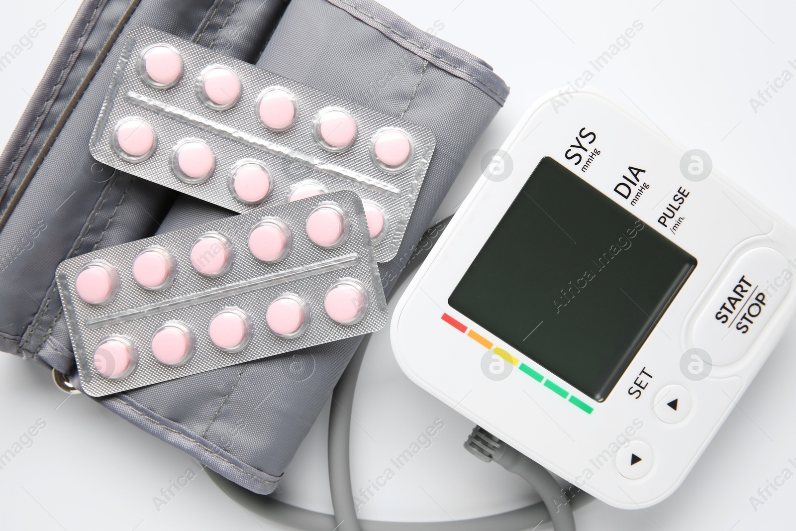 Photo of Blood pressure measuring device and pills on white background, top view