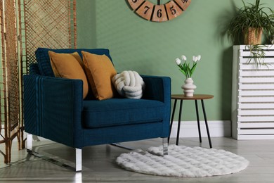 Photo of Folding screen, comfortable armchair with pillows and side table in room