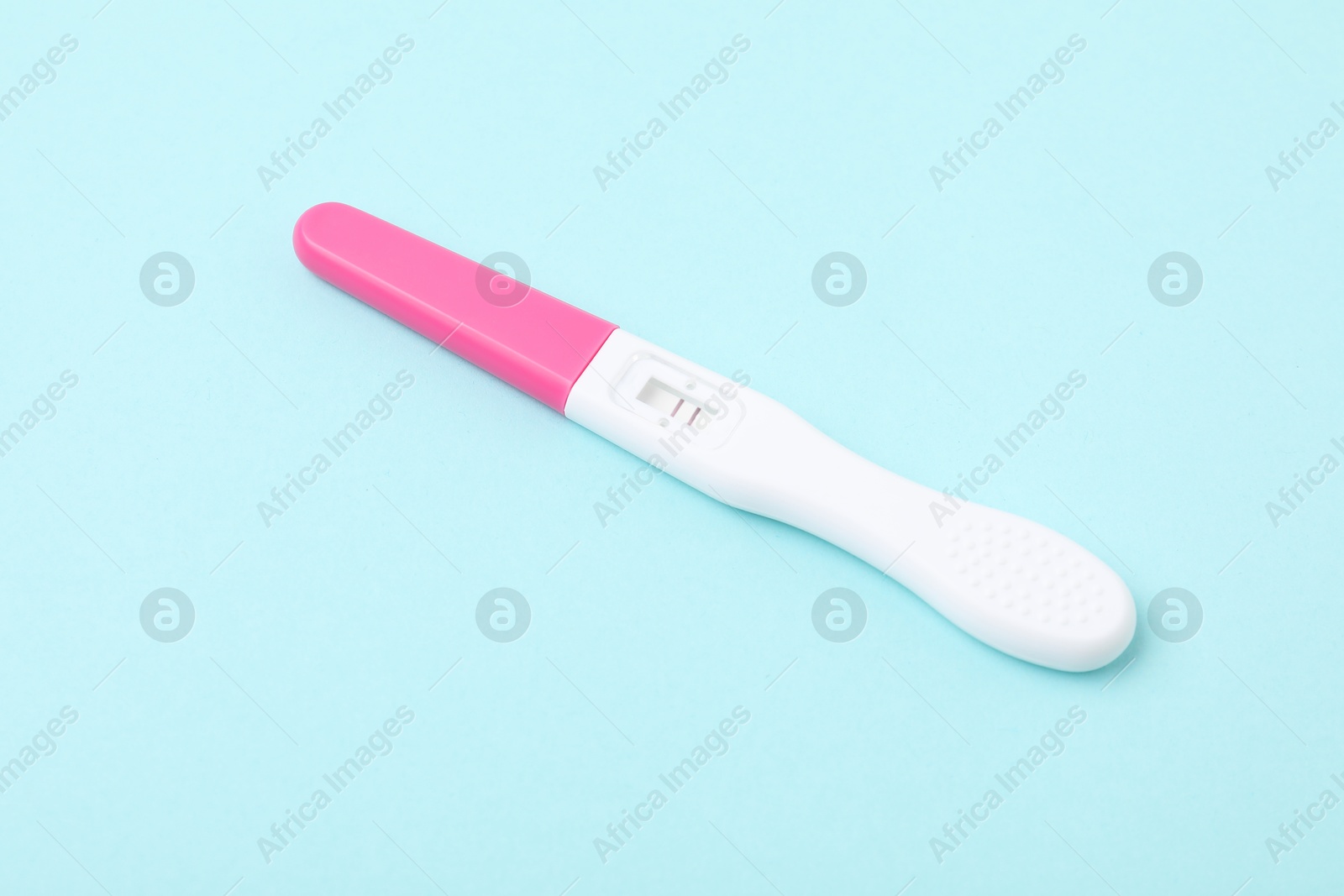 Photo of One pregnancy test on light blue background, closeup