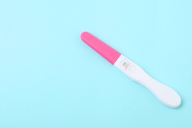 Photo of One pregnancy test on light blue background, closeup. Space for text