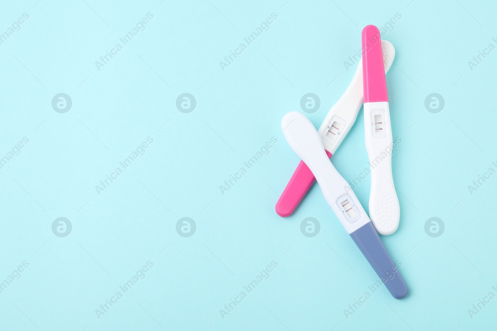 Photo of Pregnancy tests on light blue background, top view. Space for text