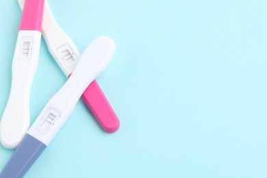 Photo of Pregnancy tests on light blue background, closeup. Space for text